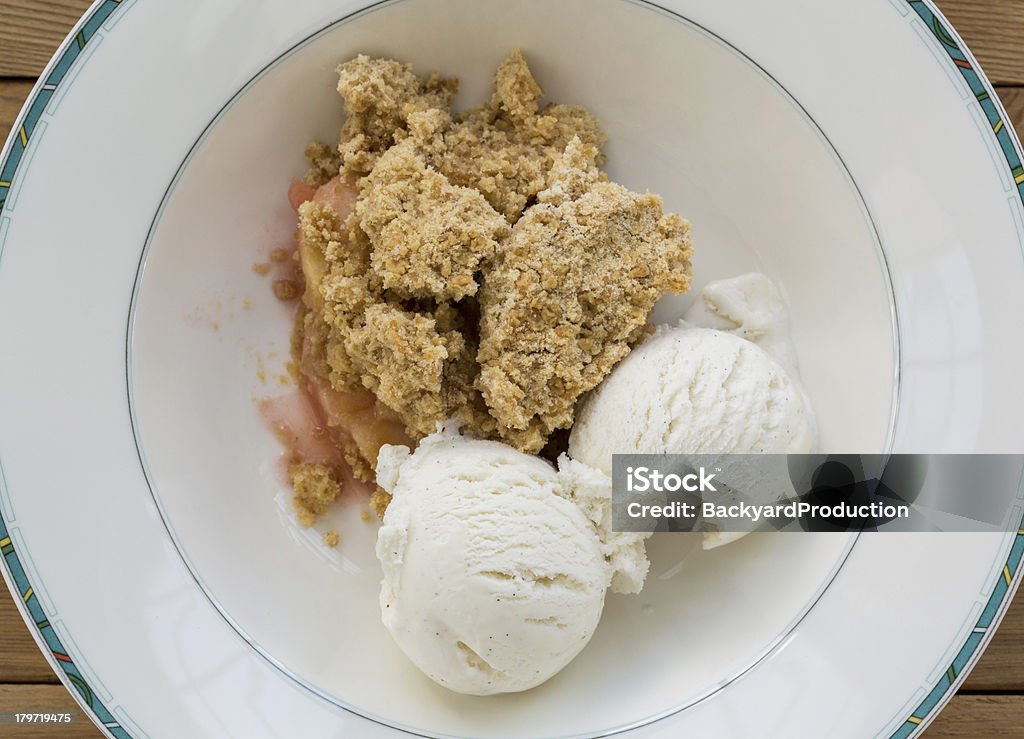 Traditional british apple crumble pie in dish with ice cream Fresh out of oven in white china bowl apple and strawberry crumble pie in traditional english dessert or pudding with vanilla ice cream scoops Apple Crumble Stock Photo