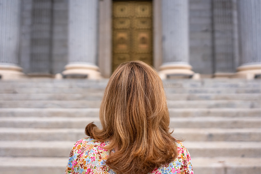 Woman with her back turned in front of the stairs of the main facade of the Congress of Deputies Madrid, Spain.