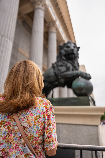 Woman with her back turned in front of the statue of lions in the Congress of Deputies in Madrid, Spain.