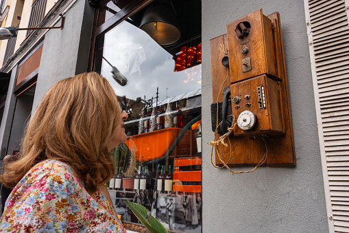 Tourist woman looking at a very old wooden phone on display on a street in Madrid, Spain
