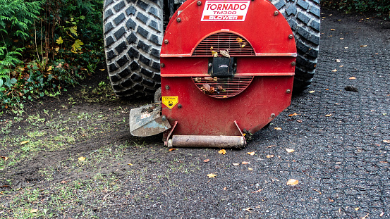 Close-up of a heavy-duty Tornado TM300 blower with a caution sign, used for landscaping and leaf removal.