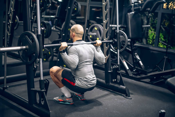 istock Young man doing squats with barbell in gym 1797211429