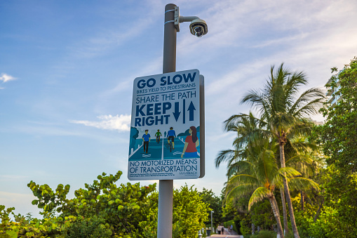 Miami Beach, USA. 11.16.2023. View of responsive poster on pole by Walking Street, urging proper walking etiquette, on blue sky background.