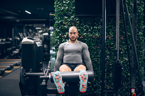 Young Man Training On A Leg Machine In The Gym