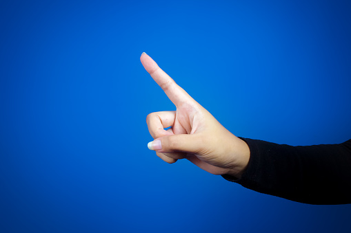 Hand or index finger. Isolated on blue background. A pointing, number one, or warning sign.