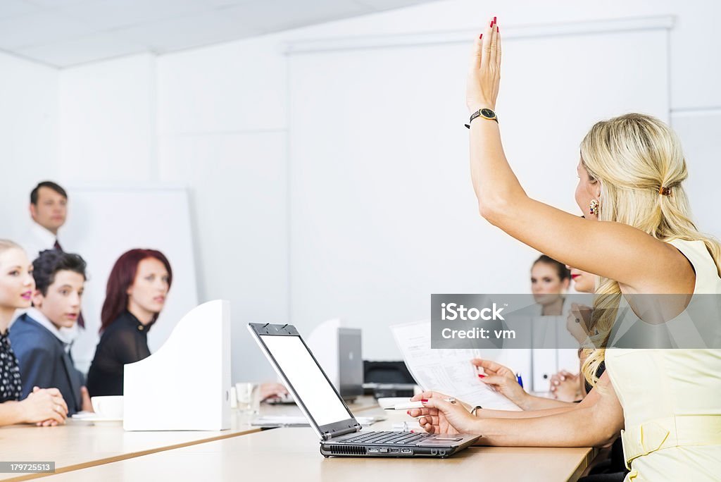 Mature women raising hand to ask question during seminar Young businessman giving a lecture to a group of business people at conference room. Activity Stock Photo