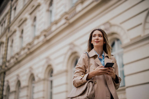 istock Smiling woman using mobile phone while outside on a city street 1797292743