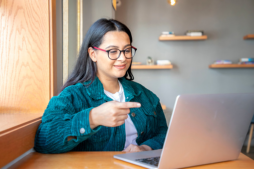 Young Latin woman with glasses works on her laptop