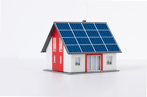 Model house with a solar panel on the roof on a white background