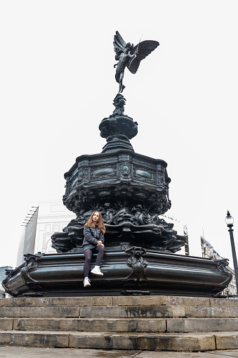 Teenage Traveler in London Posing under the Eros Statue in  Piccadilly Circus, London, UK