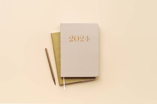 Year 2024 diary planner on a beige background, top view