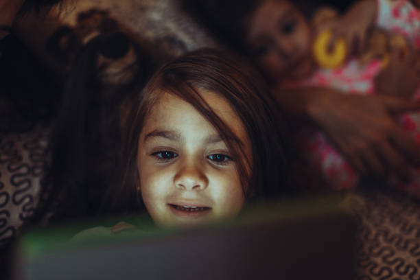 istock Little girls relaxing at home: watching digital tablets 1797392200