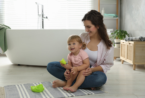 Mother playing with her daughter in bathroom