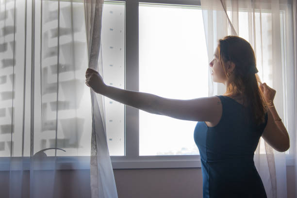istock Woman in backlight opening curtain on bright day 1797447427