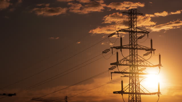 Voltage steel power pylon and evening sun, silhouette of power transmission lines electricity grid in sunset light