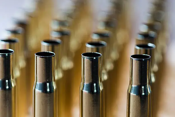 Lines of rifle cartriges waiting to be loaded with background in soft focus