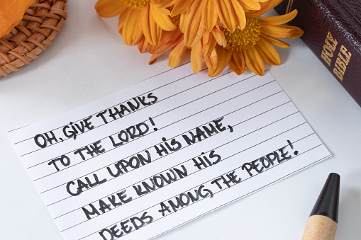 Give thanks to the LORD, handwritten Christian verse with pumpkin, autumn flowers, and holy bible. Thanksgiving, worship, and praise to God Jesus Christ, biblical concept.