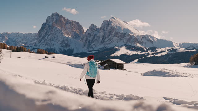 SLO MO Young Female Backpacker Walking on Snow Covered Land Along Rocky Mountains Under Sky in Dolomites