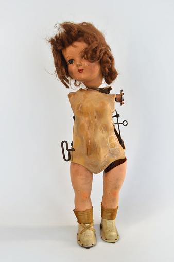 old vintage doll with broken gears partially hanging out.