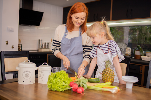 Little girl and her mother are preparing healthy food in the kitchen