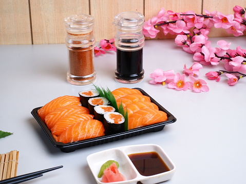 Salmon nigiri platter and some pieces salmon maki on black plate