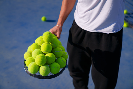 Sporty individuals are collecting tennis balls on the racket.