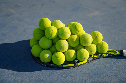Sporty individuals are collecting tennis balls on the racket.
