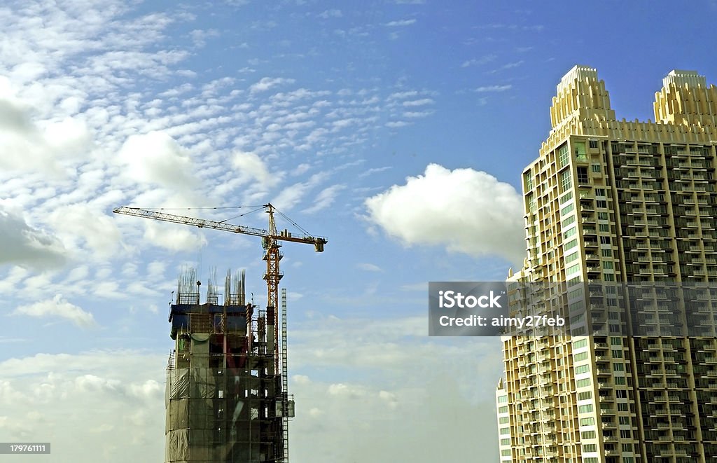 under construction with cranes against blue sky under construction with cranes against completed building with a blue sky Construction Industry Stock Photo