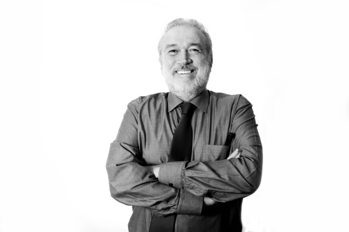 A good-looking older man resting his chin on his hand grimaces, screwing up one eye and looking to the side, where there is copy space, in irritated disbelief. Black and white image.