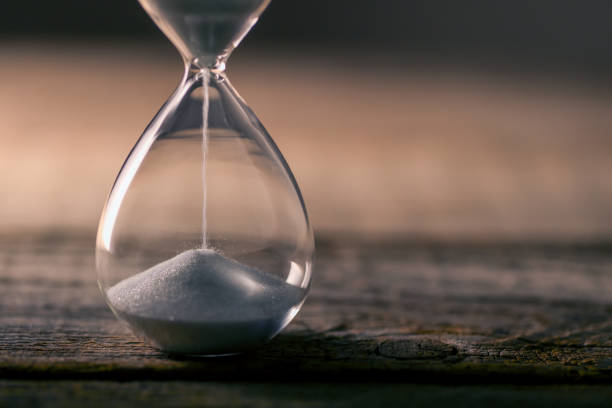 Hourglass flow Flowing white hourglass on wooden table; Twilight blue time limits stock pictures, royalty-free photos & images
