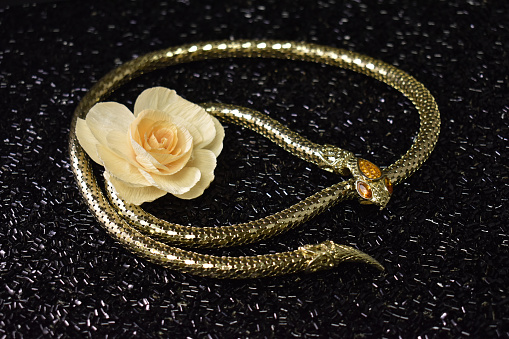 A picture of a gold snake with a rose.