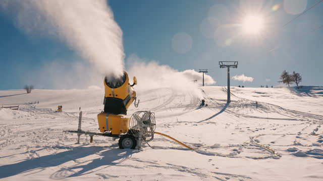 SLO MO Snow Cannon Machine Spraying Snow on Alpe Di Siusi in Dolomites Under Sunny Sky