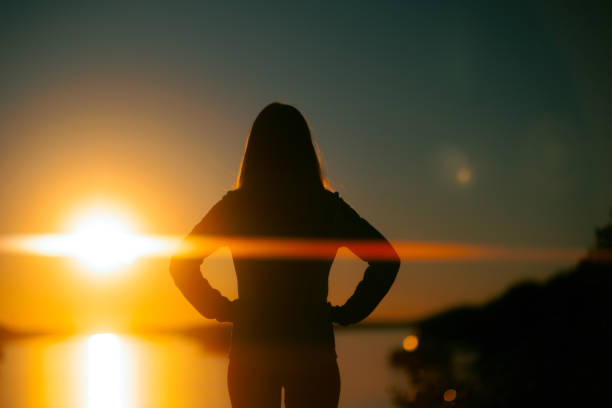 Silhouette d’une femme regardant une rivière au coucher du soleil - Photo
