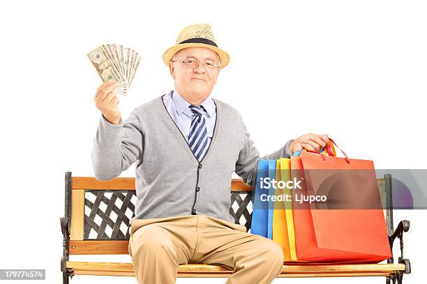 Uomo Sorridente Seduto Su Una Panchina E Holding Dollari - Fotografie stock e altre immagini di Abbigliamento