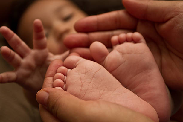 赤ちゃんの足を持つモメンタル男性のクローズアップ - human foot baby black and white newborn ストックフォトと画像