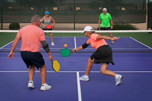 Colorful image of two teams playing Pickleball in a mixed doubles format.
