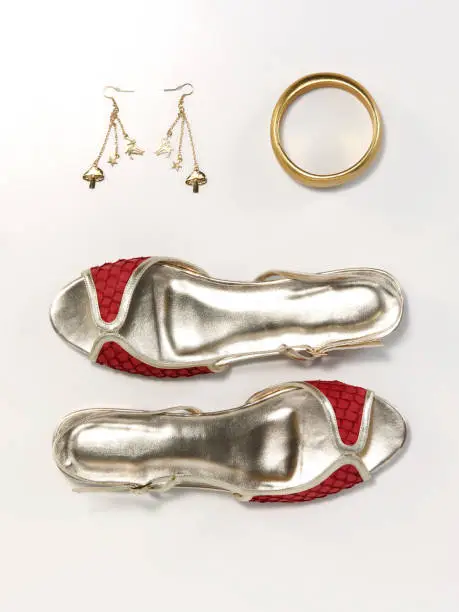 still life of a pair of silver colored shoes with bracelet and earrings