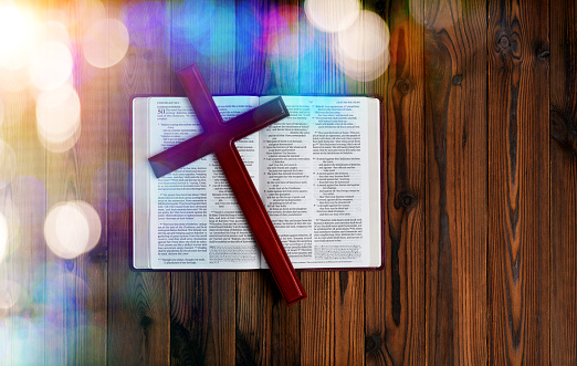Bible and religious cross on wooden table