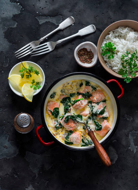 istock Delicious balanced served lunch - salmon spinach cream sauce stewed and basmati rice on a dark background, top view 1797933191