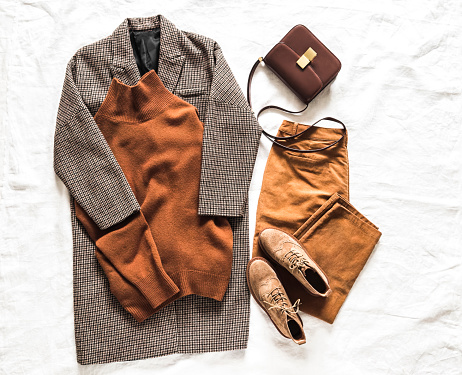 Women's clothing set - coat, cashmere sweater, suede boots, corduroy trousers, cross body bag on a light background, top view