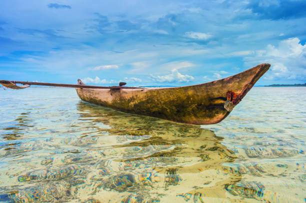 canoa anclada en una laguna tropical - canoa con balancín fotografías e imágenes de stock