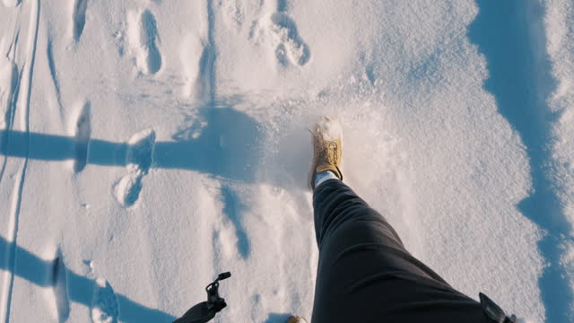 SLO MO Directly Above Shot of Legs of Unknown Hiker Walking on Snowy Field on Sunny Day