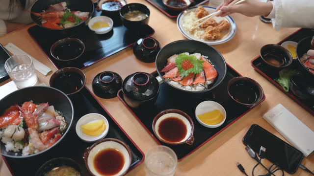 Group of tourist eating Premium fresh raw seafood mixed rice bowl Kaisen-donJapanese Rice with sashimi of tuna, Maguro, Otoro, salmon, squid and ikura (Salmon eggs)