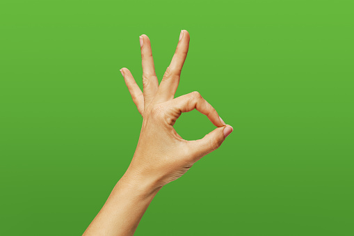 Woman hand making ok sign on green background