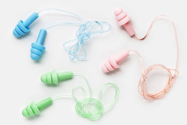 istock Reusable silicone colorful earplugs, for swim, sleep, rest as minimal trend pattern on white background. Soft, flexible ear plug on cord against noise, protect hear, close up, top view 1797990382