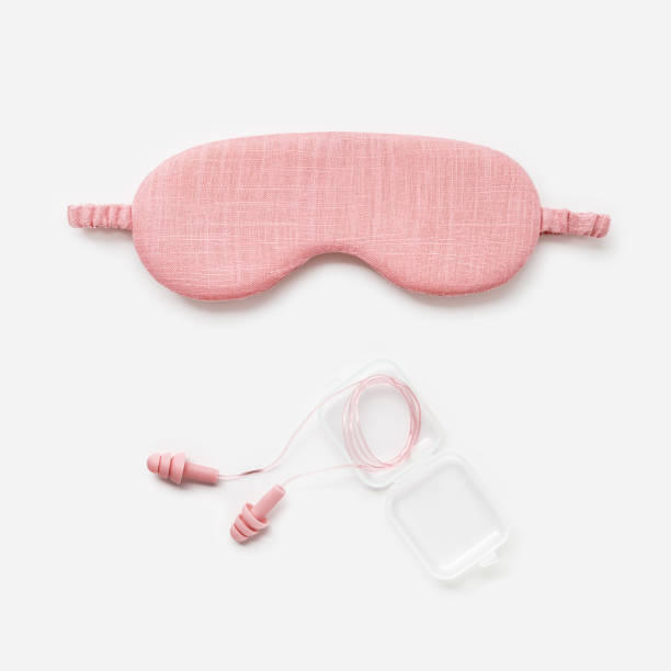 istock Sleeping mask and earplugs for healthy quality sleep on white light background. Pink colored accessories for best sleeps. Fashion silk e eye mask for travel, comfort rest, minimal top view 1798001561