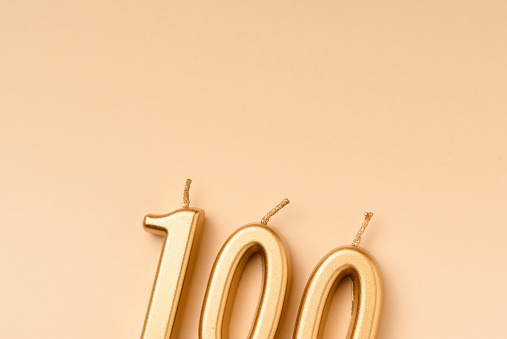 Number 100 celebration festive background made with golden candles in the form of number Hundred. Universal holiday banner with copy space.