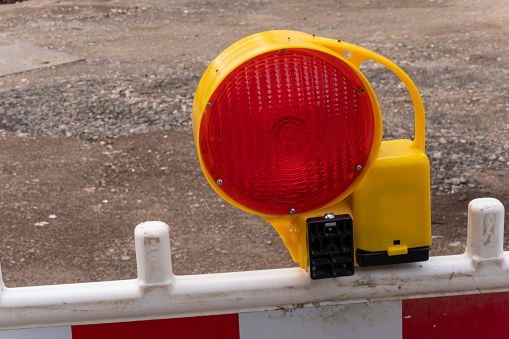 Close-up of a red warning light with street barriers at a construction site
