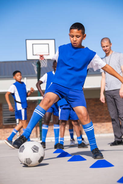 istock Schoolboy doing some soccer dribbling skills with his coach 1798027722