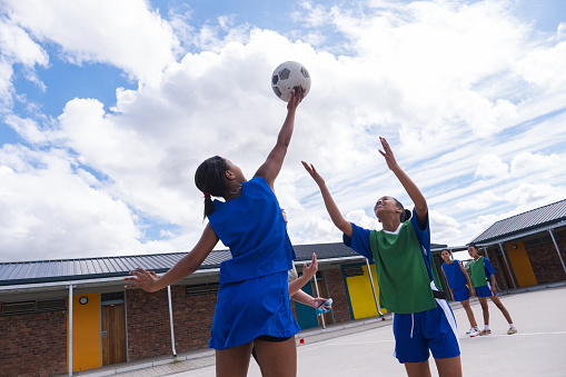 The netball coach starts the game between teenage schoolgirls. Schoolgirls from a rural school near Cape Town enjoy a friendly netball game as part of their practice